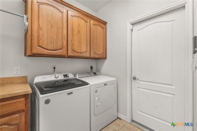 laundry area featuring light tile patterned floors, cabinet space, and separate washer and dryer