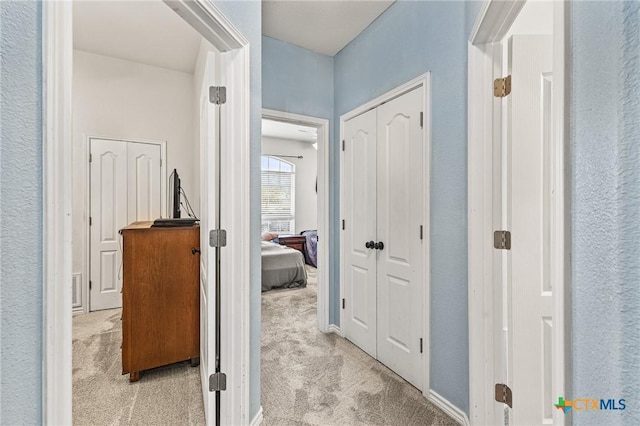 hallway featuring visible vents and light colored carpet