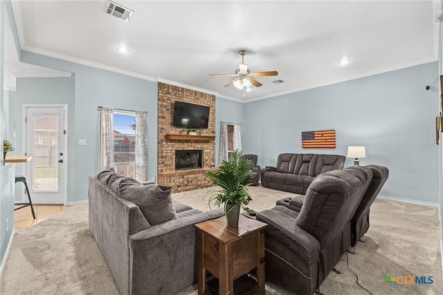 living room featuring visible vents, a brick fireplace, crown molding, and ceiling fan