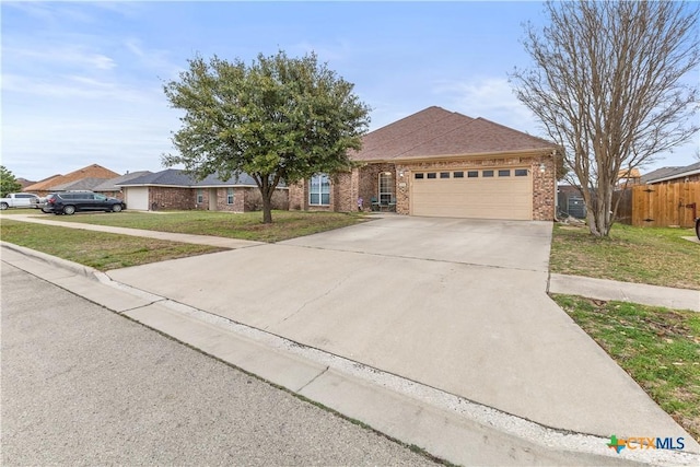 single story home featuring brick siding, a front lawn, fence, driveway, and an attached garage