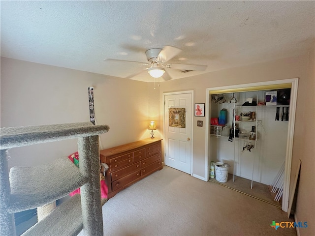 carpeted bedroom featuring a closet, a textured ceiling, and ceiling fan