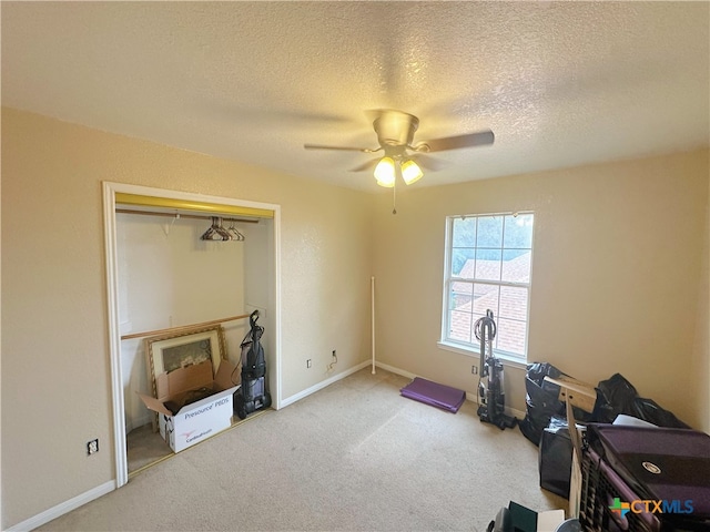 exercise room featuring a textured ceiling, carpet, and ceiling fan