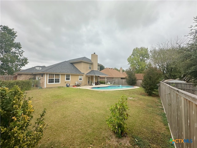 rear view of property with a fenced in pool, a patio, and a lawn