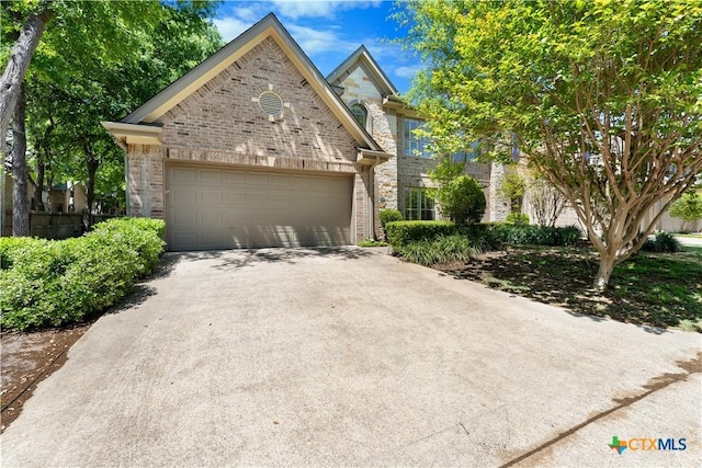 view of front facade with an attached garage, driveway, stone siding, and brick siding