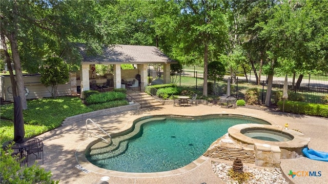 view of pool with a patio area, a pool with connected hot tub, and fence