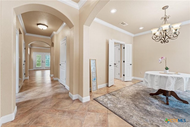 hallway featuring arched walkways, ornamental molding, visible vents, baseboards, and a notable chandelier