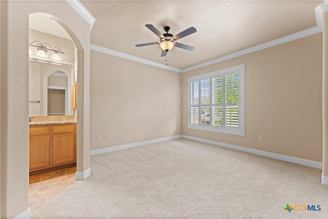 unfurnished bedroom featuring light carpet, baseboards, ornamental molding, and ensuite bath