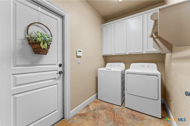 washroom featuring cabinet space, a textured wall, washer and clothes dryer, and baseboards