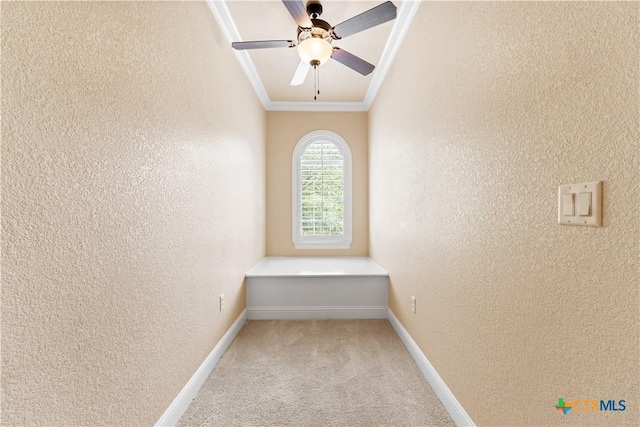 interior space with crown molding, baseboards, and a textured wall