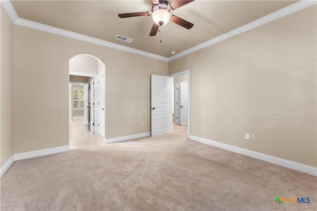 spare room featuring ornamental molding, light carpet, a ceiling fan, visible vents, and arched walkways
