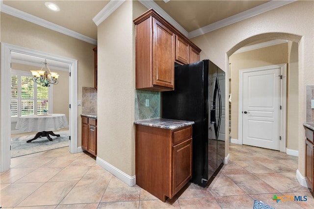 kitchen featuring tasteful backsplash, an inviting chandelier, black refrigerator with ice dispenser, brown cabinets, and arched walkways