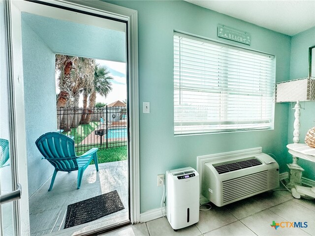 doorway with light tile patterned flooring and an AC wall unit