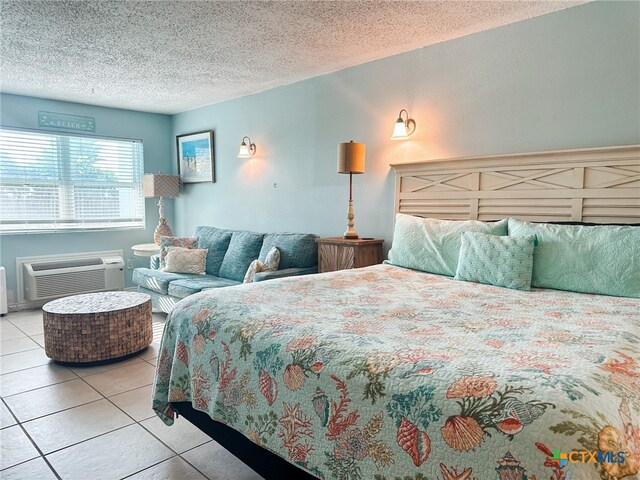 tiled bedroom featuring a wall mounted AC and a textured ceiling