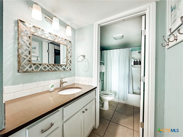 full bathroom featuring shower / bath combination with curtain, tile patterned floors, vanity, a textured ceiling, and toilet