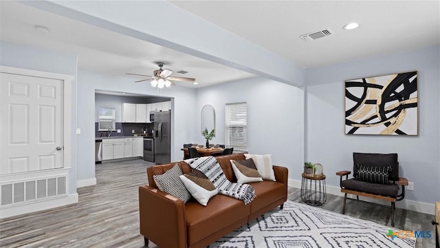 living room featuring ceiling fan, sink, and light hardwood / wood-style floors