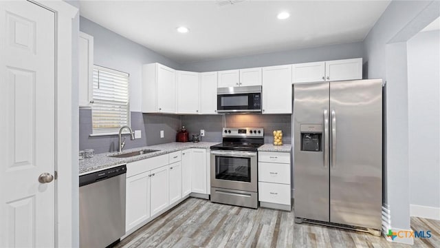 kitchen featuring light stone countertops, stainless steel appliances, white cabinets, and sink