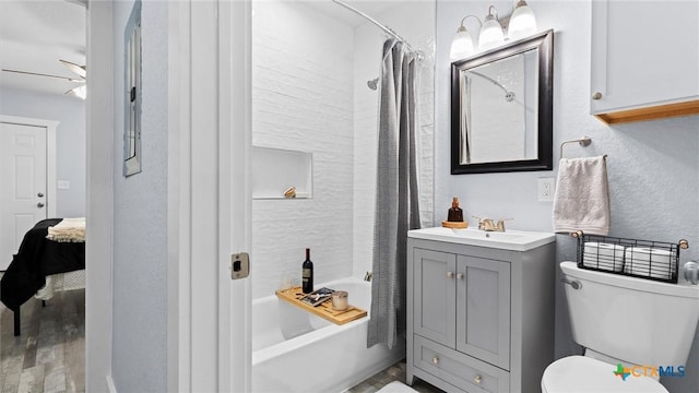 full bathroom with ceiling fan, toilet, vanity, and shower / tub combo with curtain