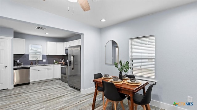 dining room featuring a healthy amount of sunlight, light wood-type flooring, and sink