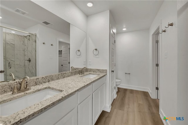 bathroom featuring wood-type flooring, toilet, an enclosed shower, and vanity