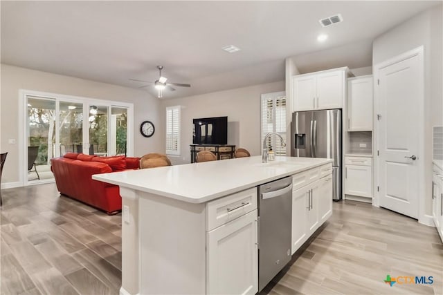 kitchen with white cabinetry, sink, stainless steel appliances, and a center island with sink