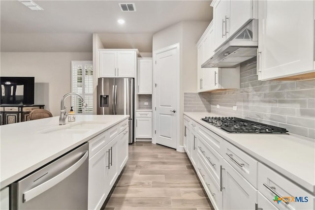 kitchen featuring appliances with stainless steel finishes, sink, white cabinets, and decorative backsplash