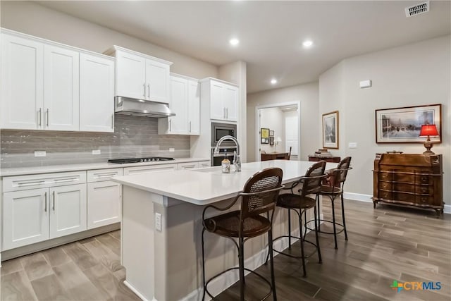 kitchen featuring a kitchen island with sink, a kitchen breakfast bar, and white cabinets