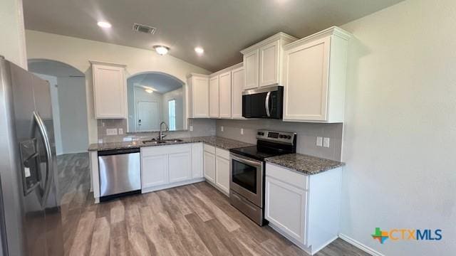 249 Bethann Dr, Temple, TX 76502 - kitchen featuring stainless steel appliances, arched walkways, wood finished floors, tasteful backsplash, and white cabinets