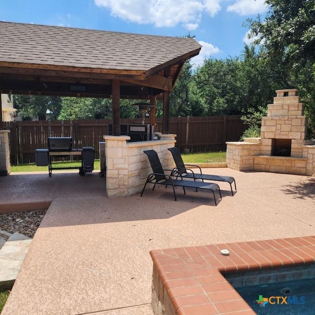 view of patio with a gazebo, a bar, and an outdoor stone fireplace