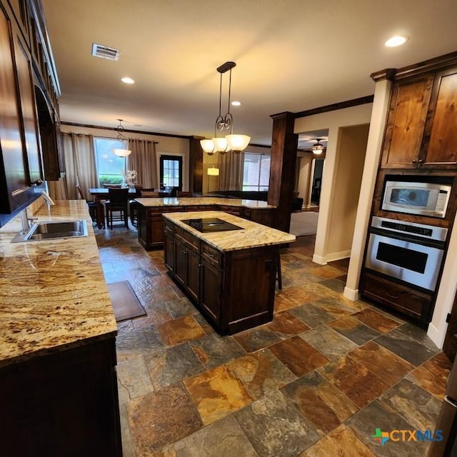 kitchen with sink, a center island, hanging light fixtures, appliances with stainless steel finishes, and light stone countertops