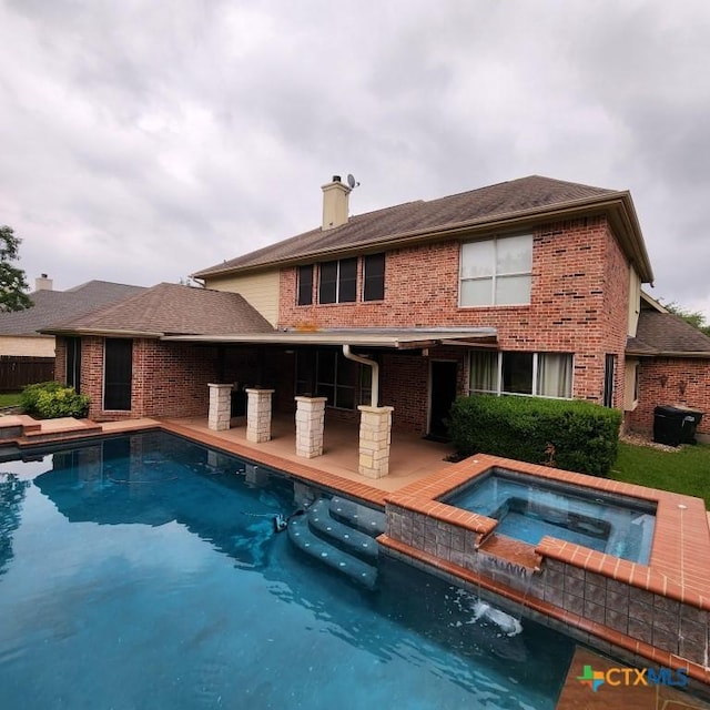 rear view of property with a swimming pool with hot tub