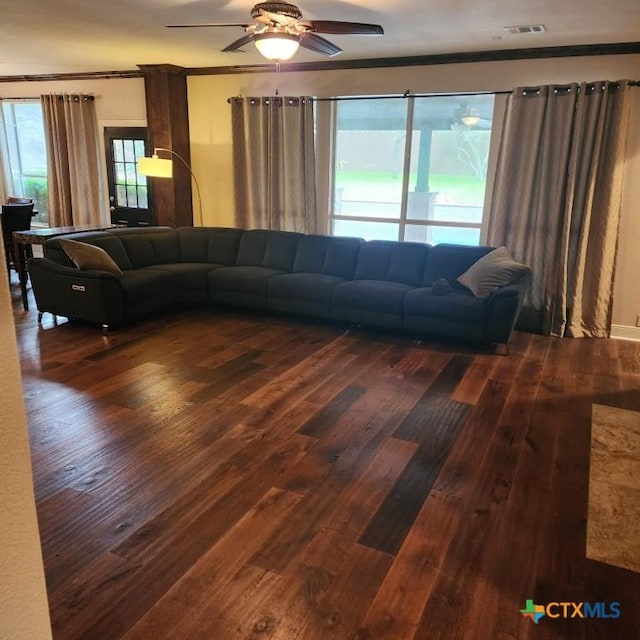 living room with crown molding, dark wood-type flooring, and ceiling fan