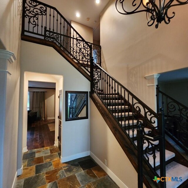 11710 Uplands Ridge Dr, Austin, TX 78738 - staircase with baseboards, stone tile flooring, a high ceiling, a chandelier, and recessed lighting