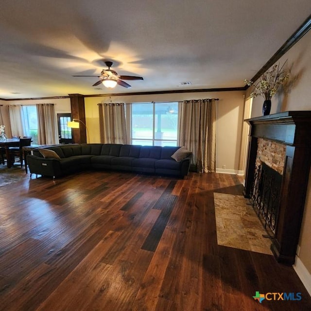 living room with dark wood-type flooring, ceiling fan, ornamental molding, and a fireplace