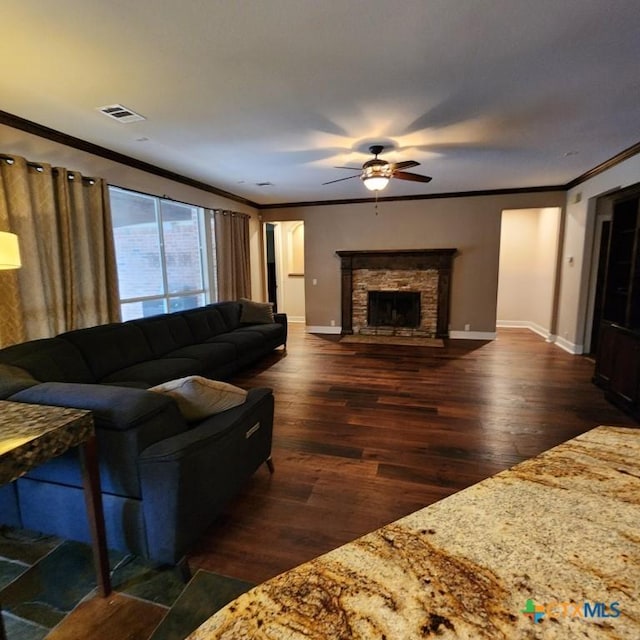 living room with dark wood-type flooring, a fireplace, ornamental molding, and ceiling fan