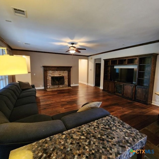 living room featuring crown molding, dark hardwood / wood-style floors, ceiling fan, and a fireplace