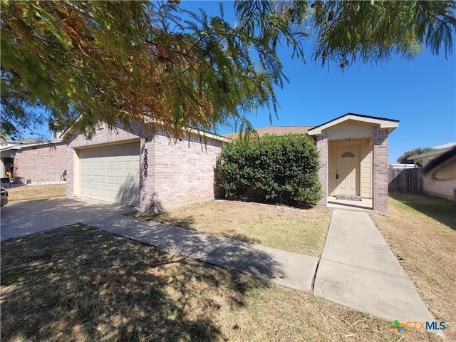 single story home featuring a front yard, fence, concrete driveway, and brick siding