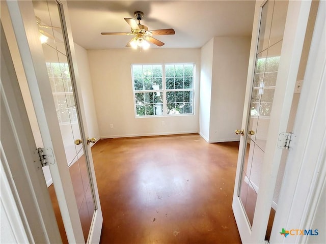 unfurnished room with ceiling fan and concrete flooring