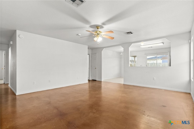 spare room with ceiling fan, finished concrete floors, visible vents, and baseboards