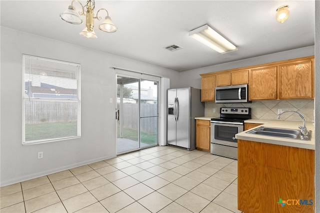 kitchen featuring sink, decorative light fixtures, appliances with stainless steel finishes, a notable chandelier, and light tile patterned flooring