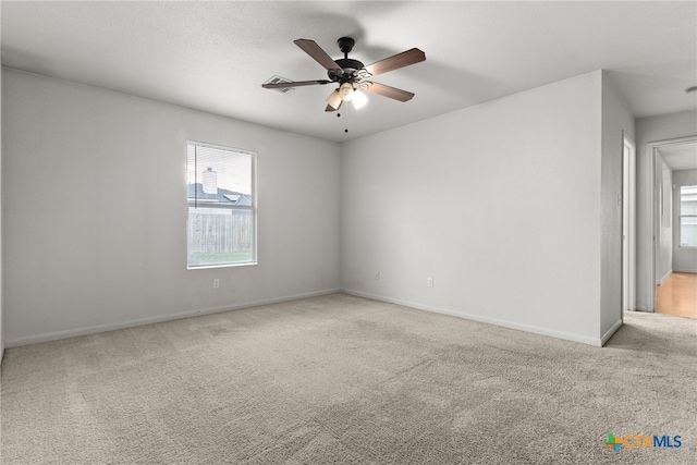 empty room featuring baseboards, a ceiling fan, and light colored carpet