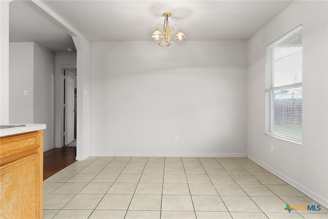 empty room featuring light tile patterned floors and a notable chandelier