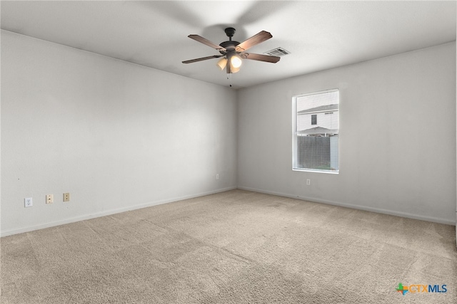 carpeted empty room with ceiling fan, visible vents, and baseboards