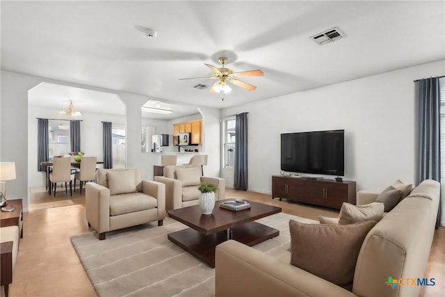 living area with visible vents and ceiling fan with notable chandelier