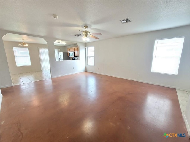 empty room featuring ceiling fan with notable chandelier and a textured ceiling