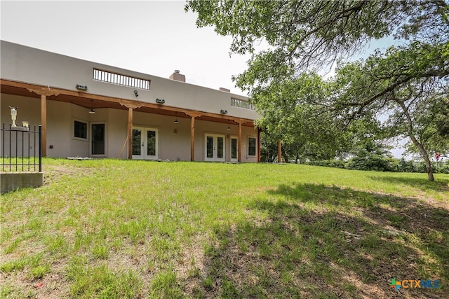 rear view of property with french doors and a yard