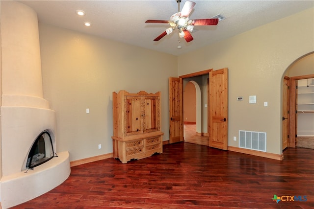 unfurnished living room featuring dark wood-type flooring, ceiling fan, and a textured ceiling