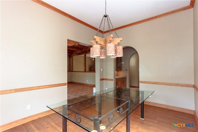 9776 Arroyo Dr, Belton, TX 76513 - unfurnished dining area with arched walkways, wood finished floors, baseboards, ornamental molding, and a chandelier