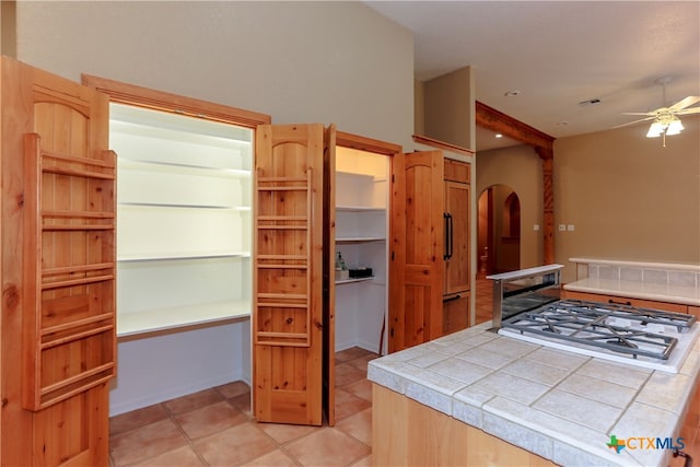 kitchen with tile counters, ceiling fan, and light tile patterned floors