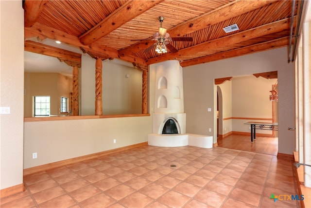 unfurnished living room featuring wooden ceiling, beamed ceiling, a large fireplace, and ceiling fan