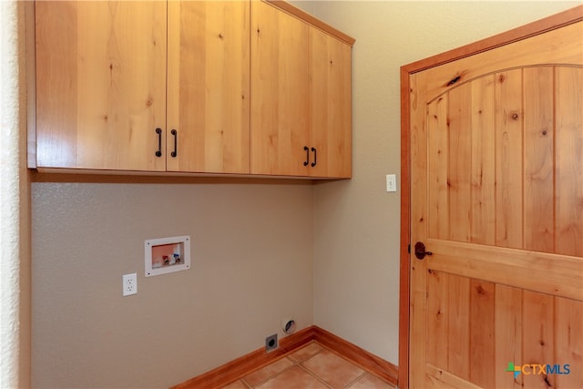 clothes washing area featuring washer hookup, cabinets, and light tile patterned floors